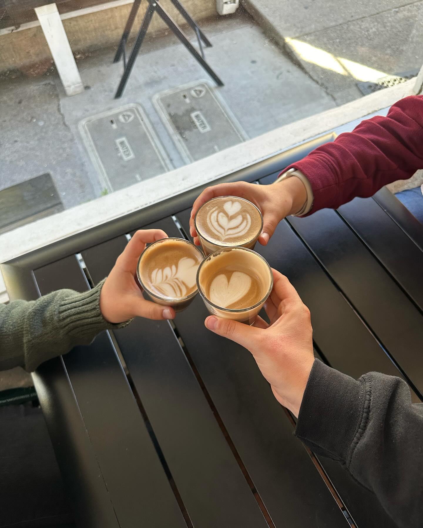 A group of 3 happy patrons display their espresso drinks